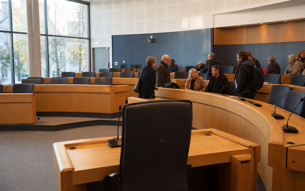 Salle de conseil municipal avec habitants prenant place avant une séance